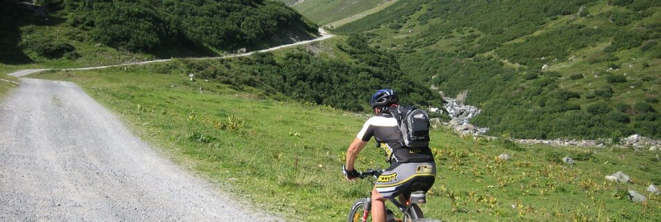 Cycliste en VTT sur les sentiers du Queyras entourés de montagnes.